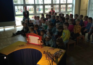 dzieci z grupy Misiów i Bulinków siedzą na ławeczkach, z przodu mini teatr z jawajskimi lalkami