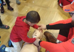 Ratownik uczy dziecko jak udzielić pierwszej pomocy