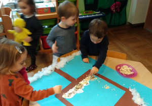 Dzieci wykonują grupową pracę plastyczną karmnik
