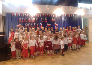 dzieci stoją przed napisem patriotycznym