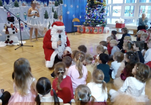 Mikołaj podchodzi do dzieci siedzących na podłodze