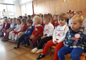 Dzieci ubrane na białoczerwono ogladają występy kolegów