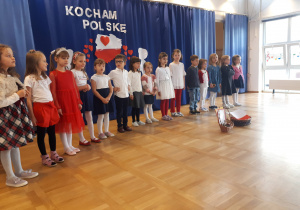 Dzieci ubrane na białoczerwono stoją na scenie