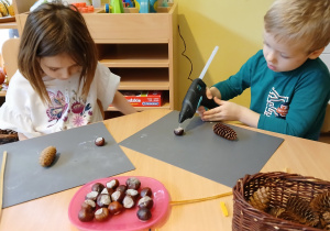 Dzieci wykonują pracę ślimaki z szyszki i kasztana