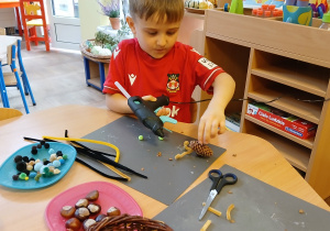 Dzieci wykonują pracę ślimaki z szyszki i kasztana