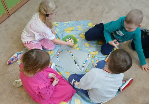 Dzieci w grupach wyklejają cyfrę 2