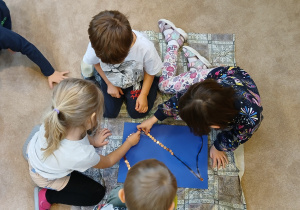 Dzieci w grupach wyklejają cyfrę 2