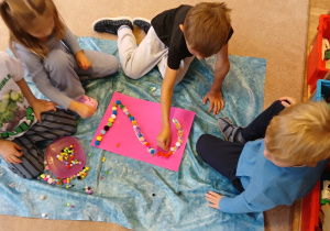 Dzieci w grupach wyklejają cyfrę 2