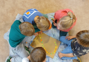 Dzieci w grupach wyklejają cyfrę 2