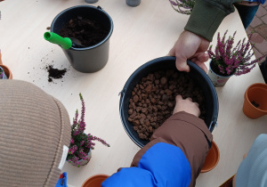 Dzieci wsypują ziemię do doniczek