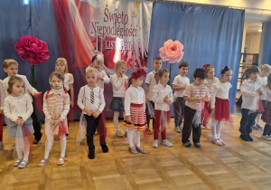 Dzieci w białoczerwonych strojach występują na scenie