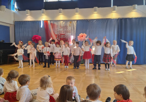 Dzieci w białoczerwonych strojach występują na scenie