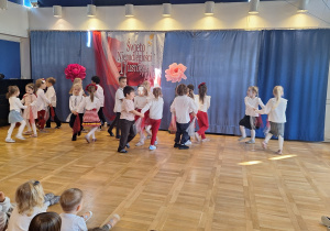 Dzieci w białoczerwonych strojach występują na scenie