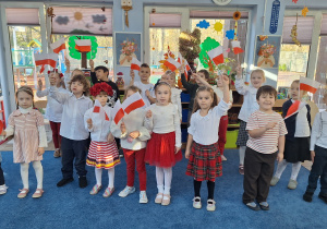 Dzieci w białoczerwonych strojach wymachują fagami