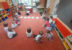 dzieci siedzą w kole na dywanie