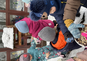 Dzieci wsypują ziarna do karmnika