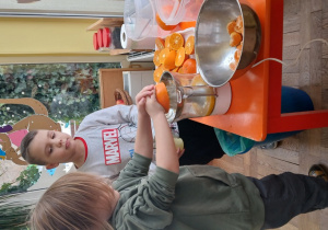 Chłopiec wyciska sok z pomarańczy