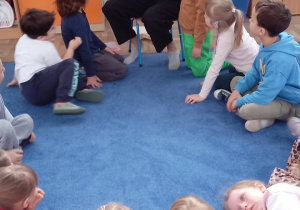 Mama czyta dzieciom książkę "Księga pytań i odpowiedzi"