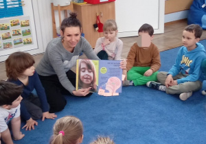 Mama czyta dzieciom książkę "Księga pytań i odpowiedzi"