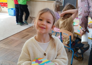 dziewczynka wykunuje pisankę z kolorowych pasków papieru