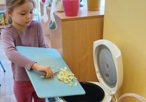 Dziewczynka przekłada pokrojone jabłka do multicoocera