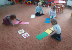 dzieci układają kolorowe kafle na dywanie