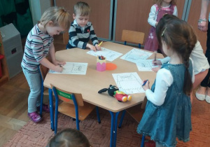 dzieci siedzą przy stoliku i kolorują
