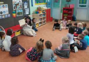 dzieci siedzą na dywanie i słuchają