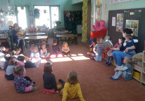 dzieci siedzą na dywanie i słuchają