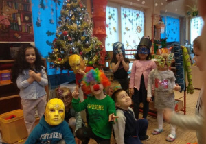 Dzieci w swojej sali pozuja do zdjecia w maskach i perukach