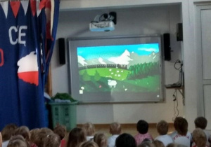 Rodzice i dzieci siedza przed tablica interaktywną i oglądają film pod tytułem Polak Mały
