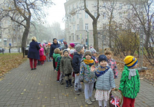 Przedszkolaki idą po alejce w parku